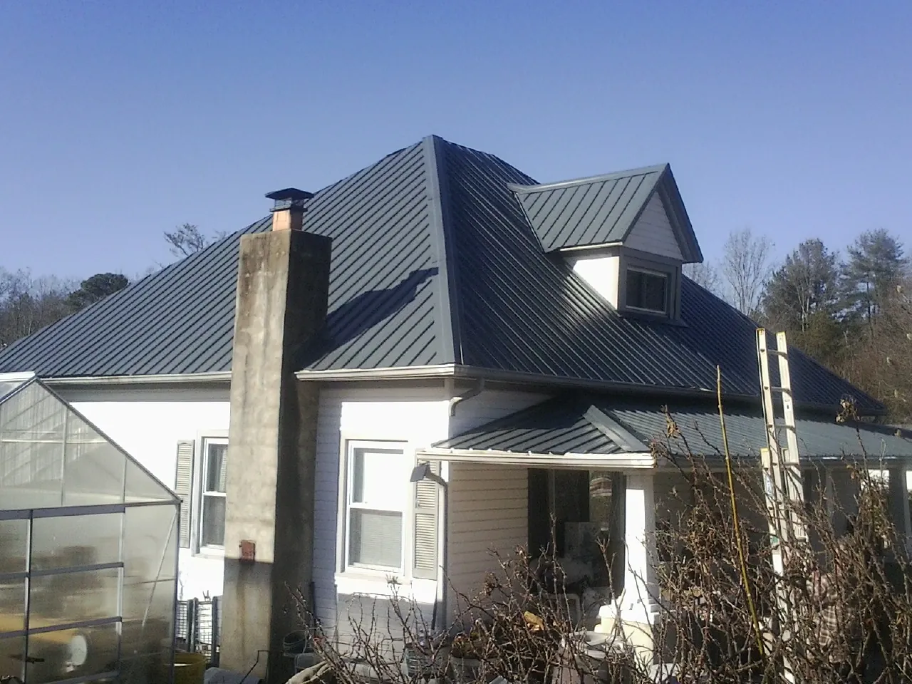 Dark blue standing seam metal roof on a white farmhouse with dormer — Slate & Tile Roof Repair by Roofing Brothers in Bloomsburg