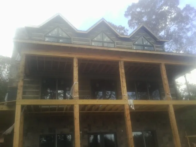 Dormers and porch framing on a large log home under construction — Roof Coating work by our crew in Bloomsburg