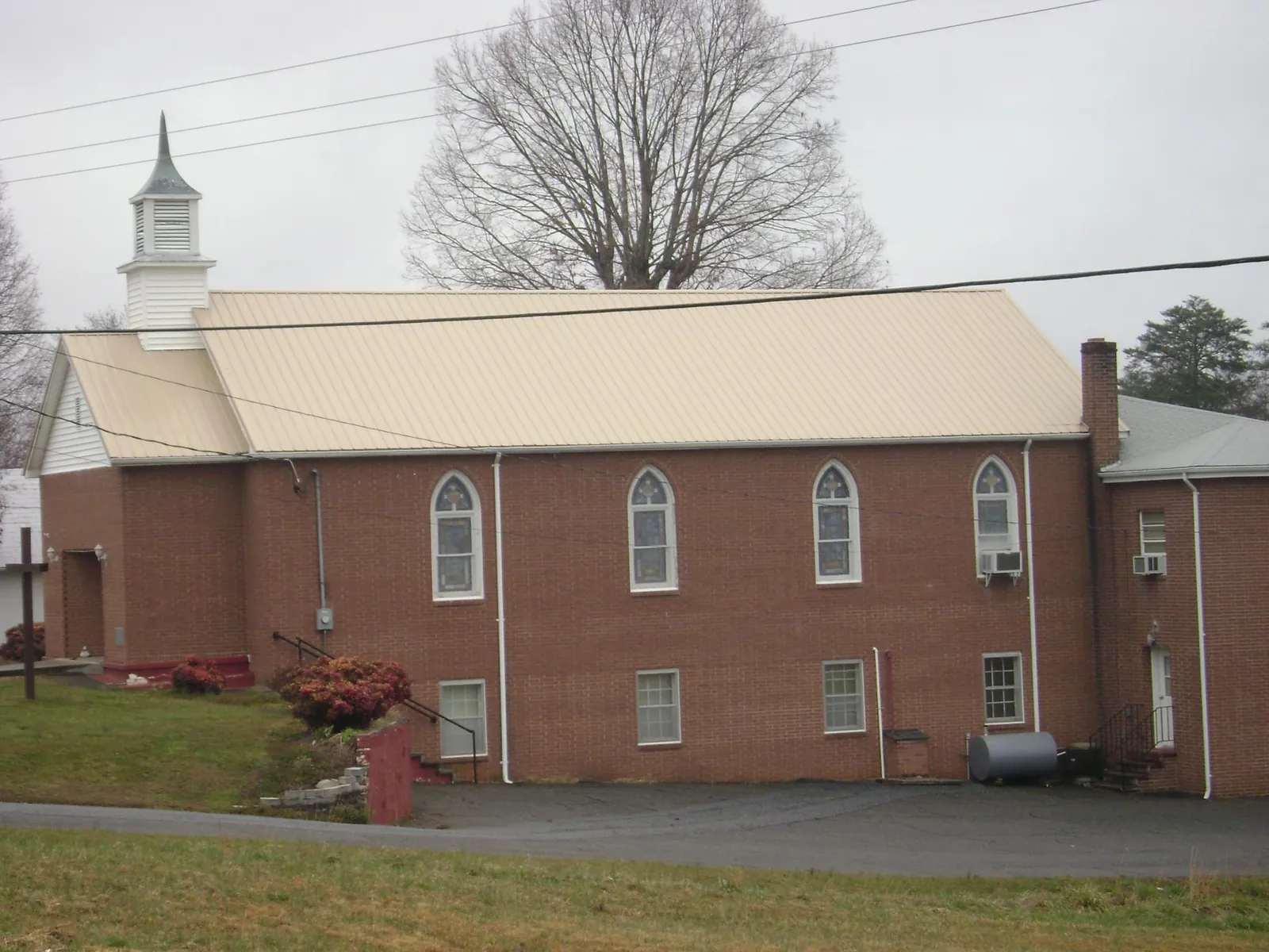 New tan metal roof on a brick church with a white steeple in Bloomsburg