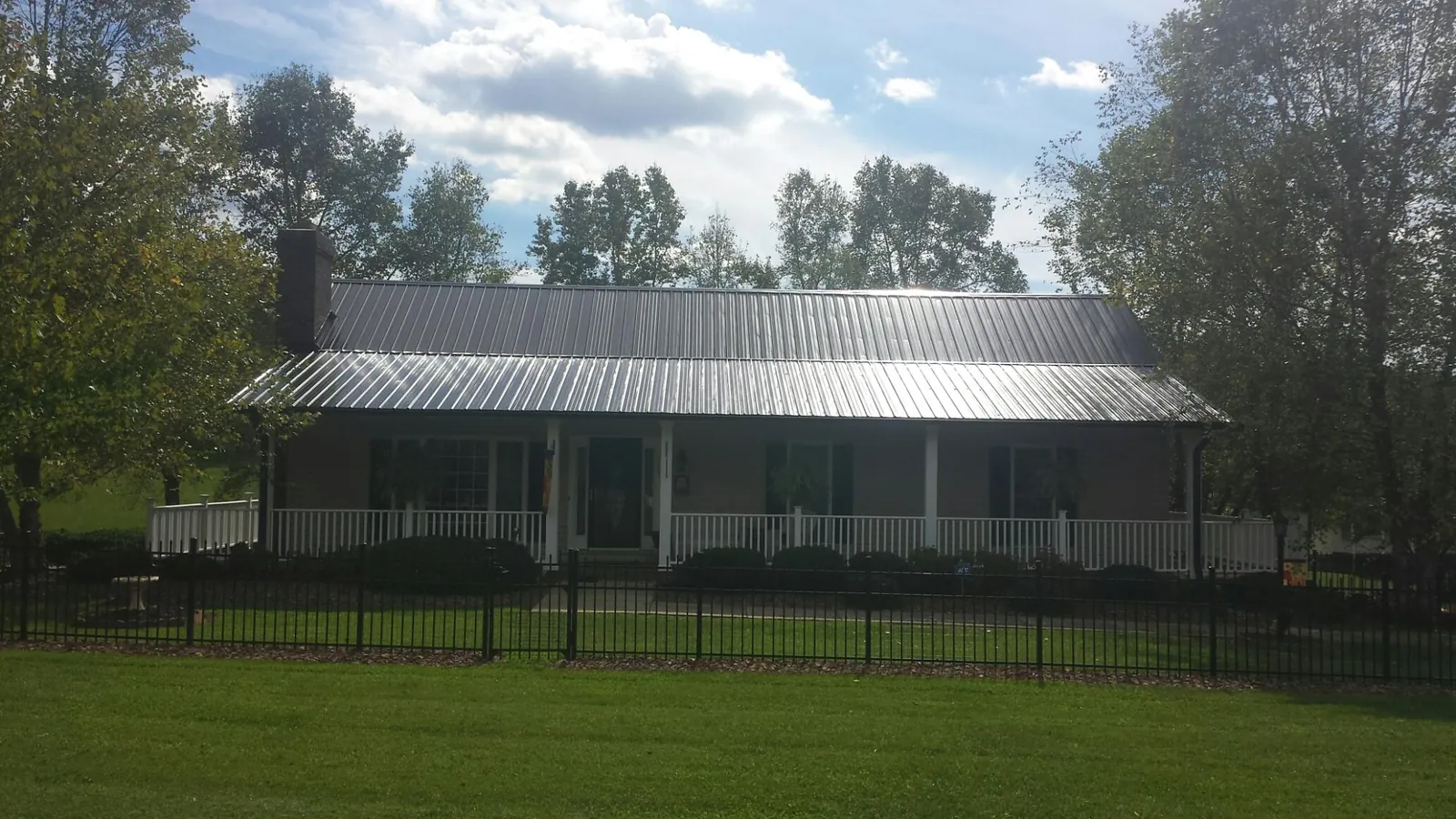 Gray metal roof on a brick ranch with a full width front porch — Gutter Guard Installation work by our crew in Bloomsburg