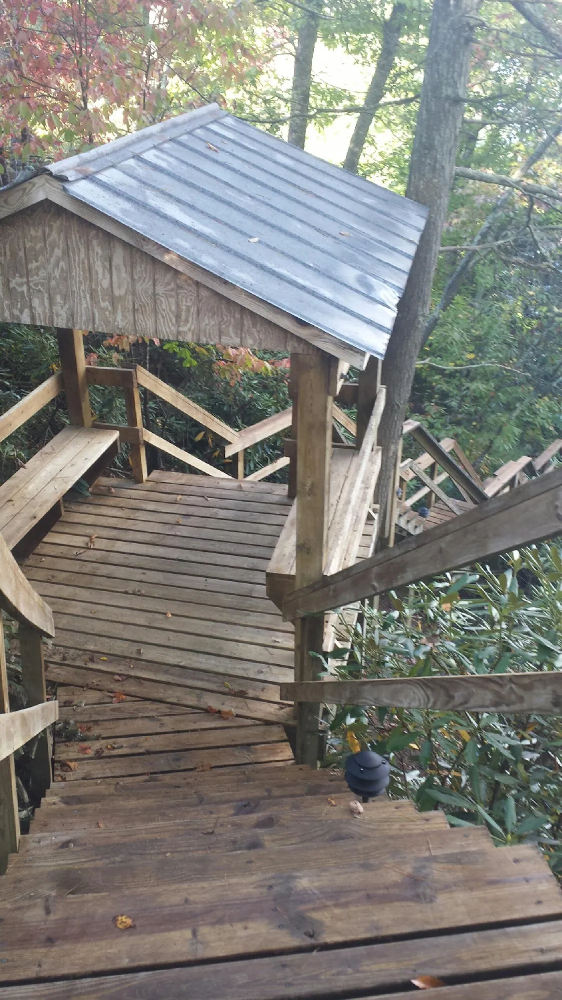 Metal roofed shelter over wooden steps on a wooded walkway — Skylight Repair & Installation work by our crew in Bloomsburg