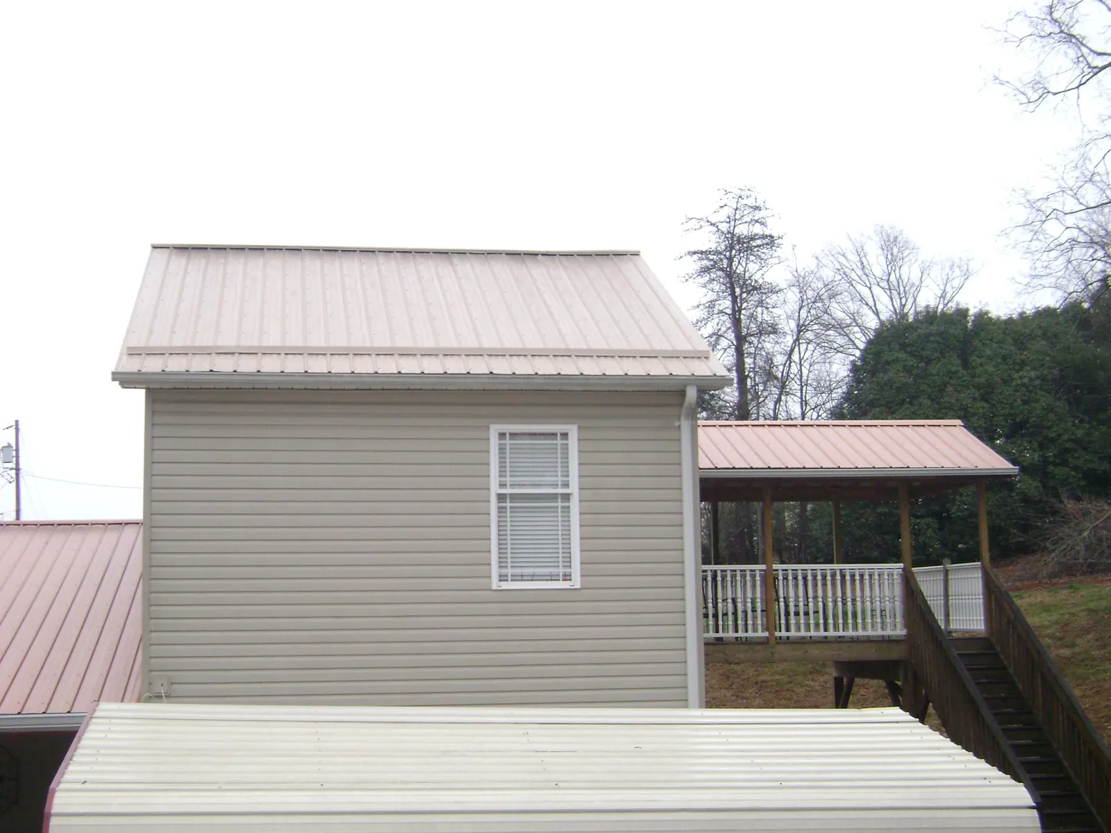 Tan metal roofs on a two story addition and attached porch, from a Roof Replacement job in Bloomsburg