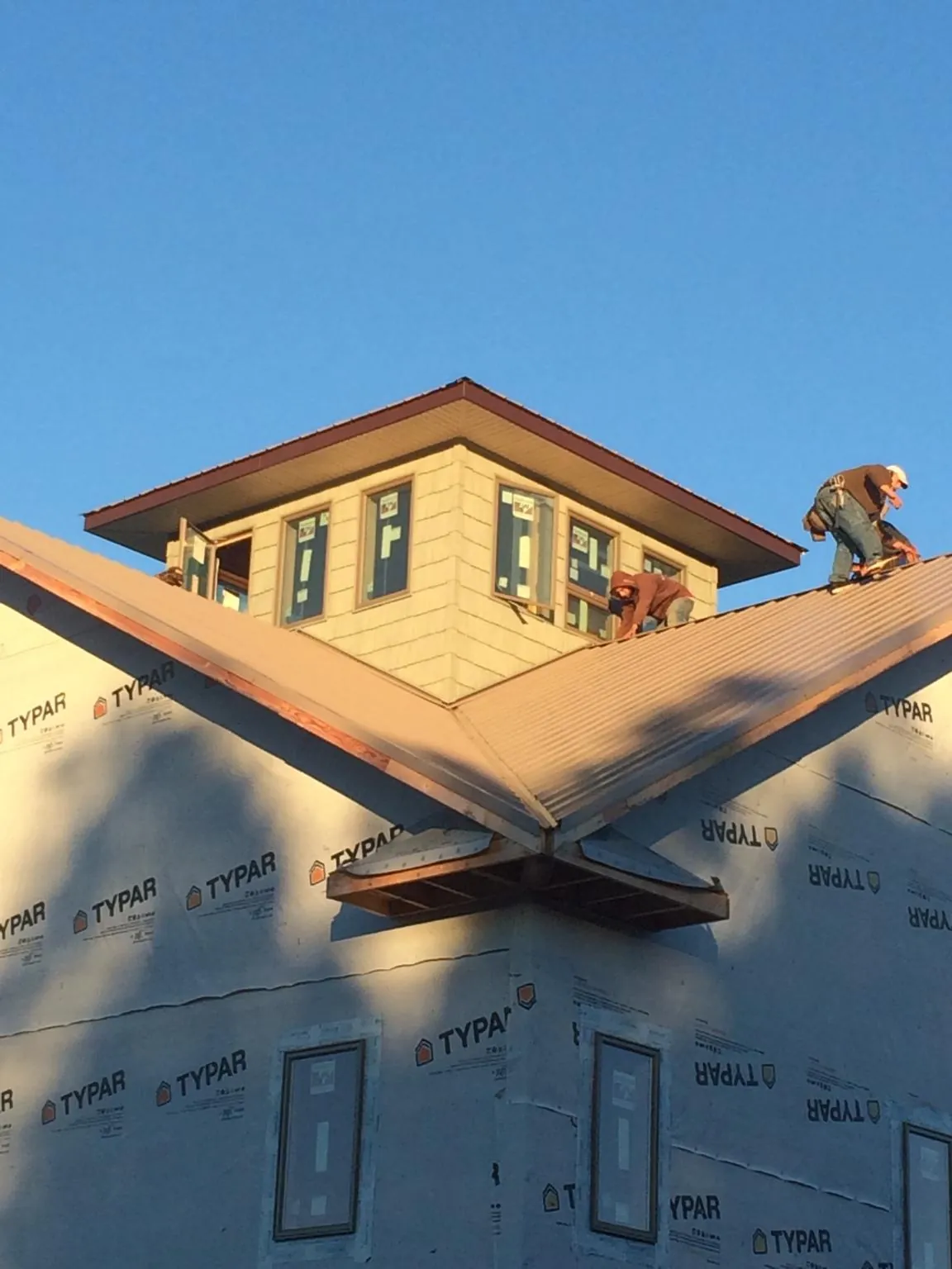 Roofers working around a rooftop cupola on a new metal roof at sunset — Roof Waterproofing in Bloomsburg by Roofing Brothers